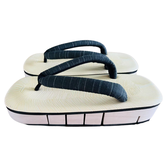 Pair of traditional Japanese sandals with white soles and dark green straps on a white background