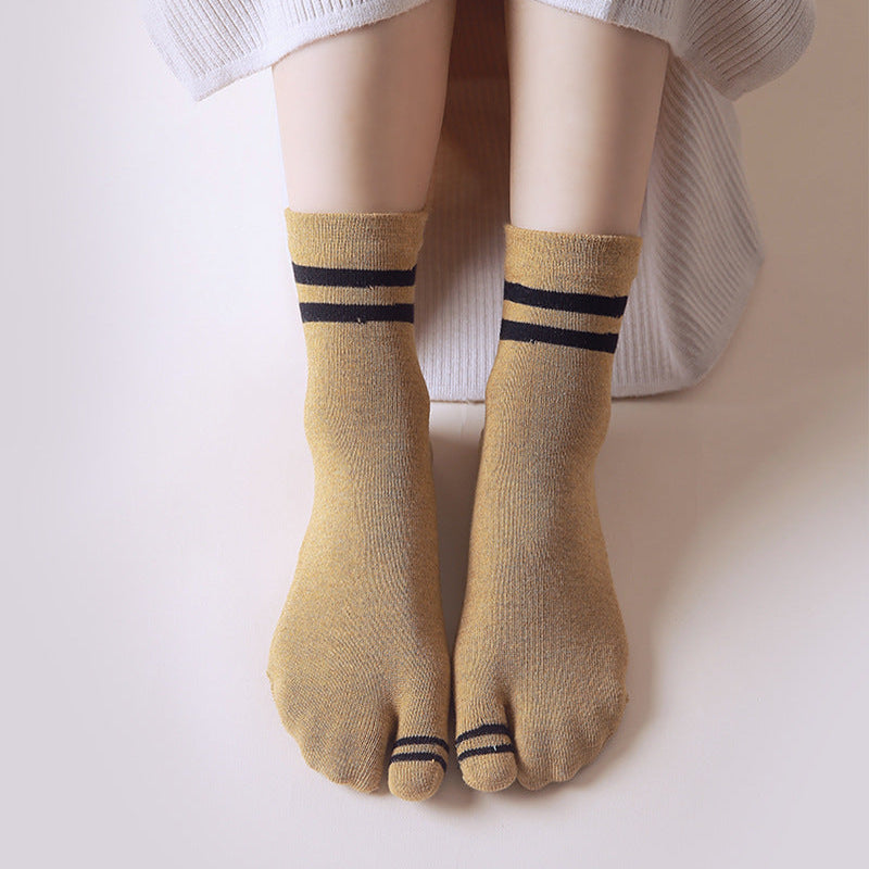 Person wearing mustard yellow socks with black stripes on a plain background