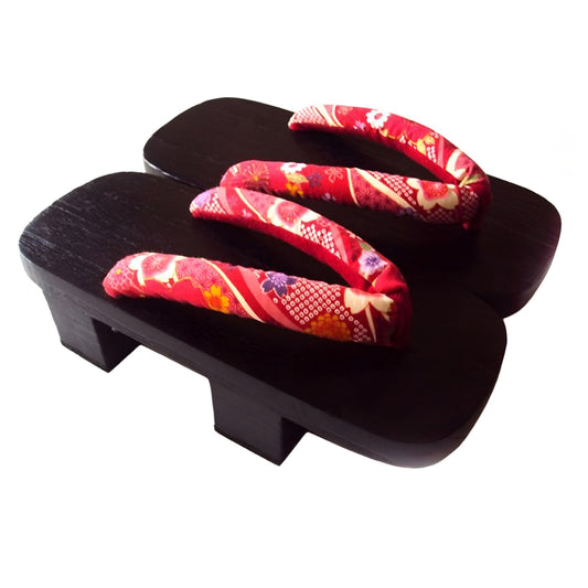 Pair of black wooden clogs with red floral straps on a white background