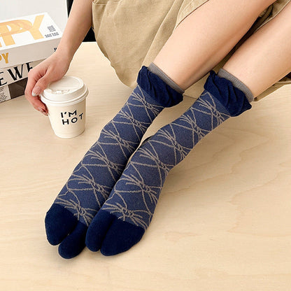 Person wearing blue patterned toe socks with a cup of coffee and laptop in the background.