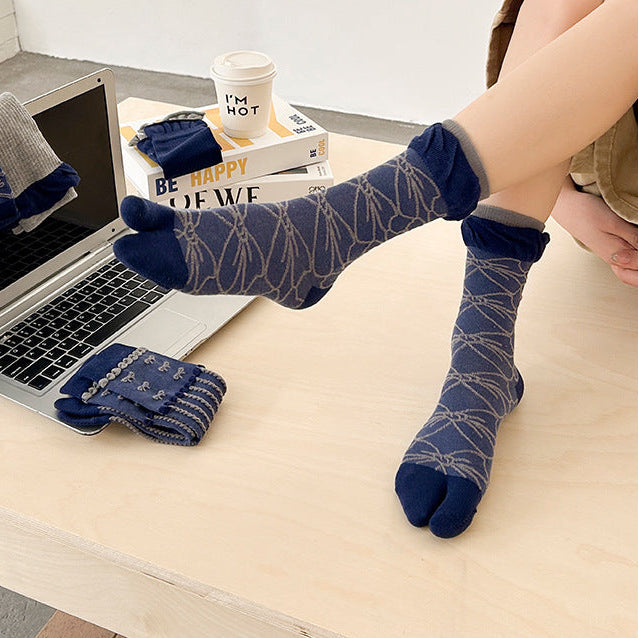 Person wearing blue patterned socks with a laptop on a desk