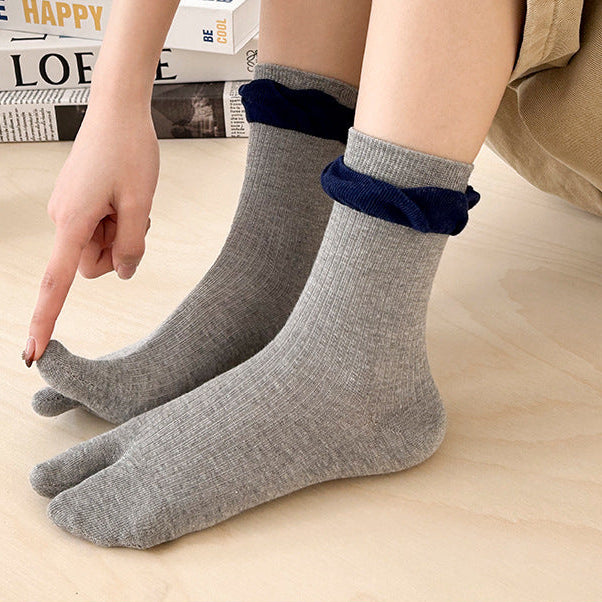 Person wearing gray socks with blue accents on a light wooden floor.
