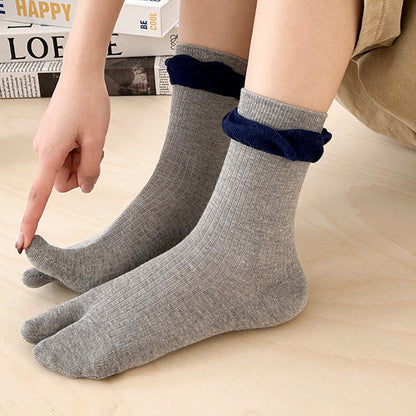 Person wearing gray socks with blue accents on a light wooden floor.