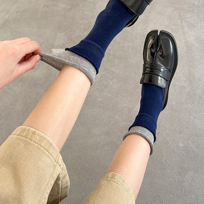 Person wearing blue socks with gray trim, standing on a concrete floor.